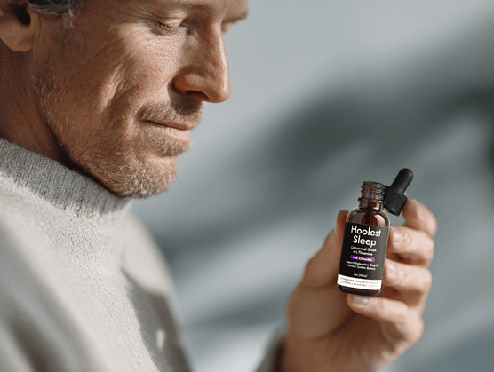 A man smiling while holding a bottle of Hoolest Sleep